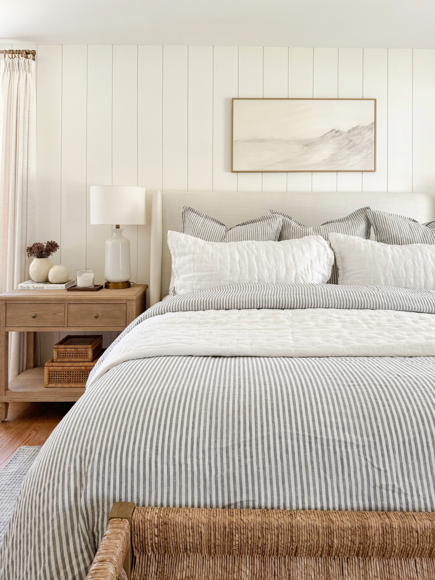 coastal master bedroom with gray striped duvet set and wood nightstands