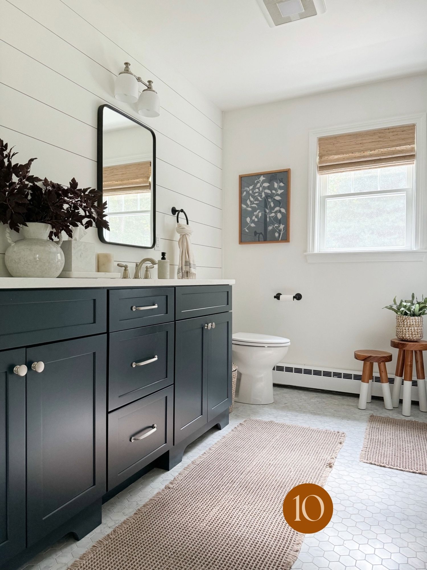coastal throw pillow inspiration Coastal farmhouse bathroom with navy vanity cabinets, white shiplap walls, woven rugs, and natural wood accents.
