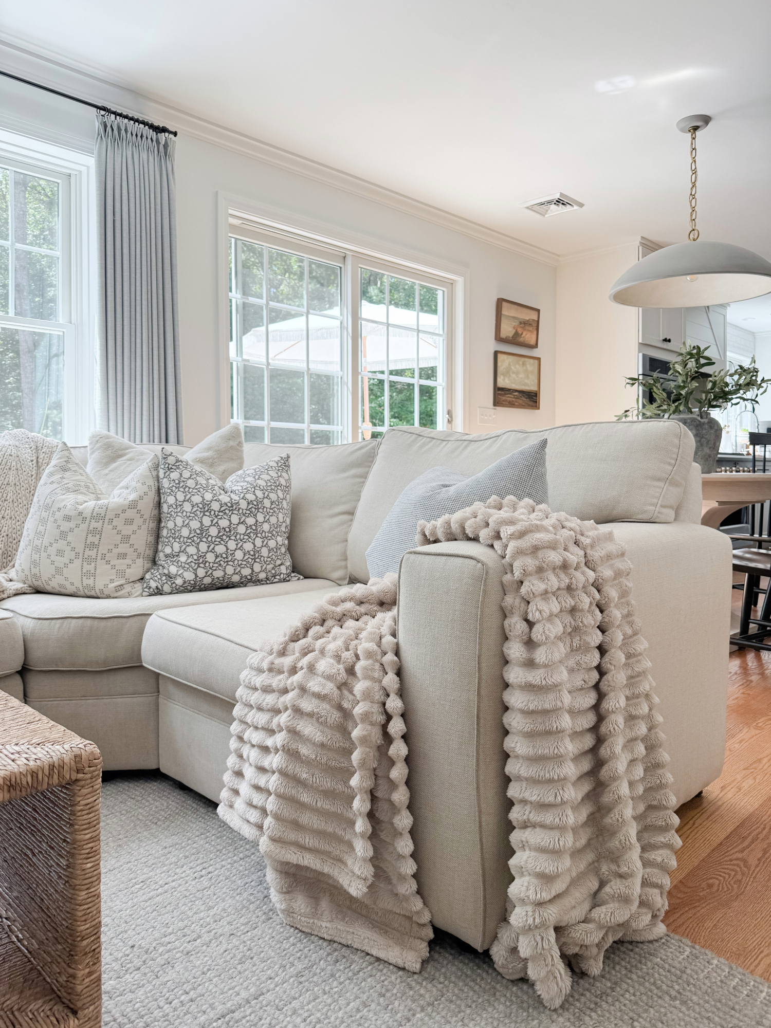 Coastal living room with neutral sectional sofa, textured throw blanket, patterned pillows, and soft area rug. Coastal style Amazon Prime Day home decor.