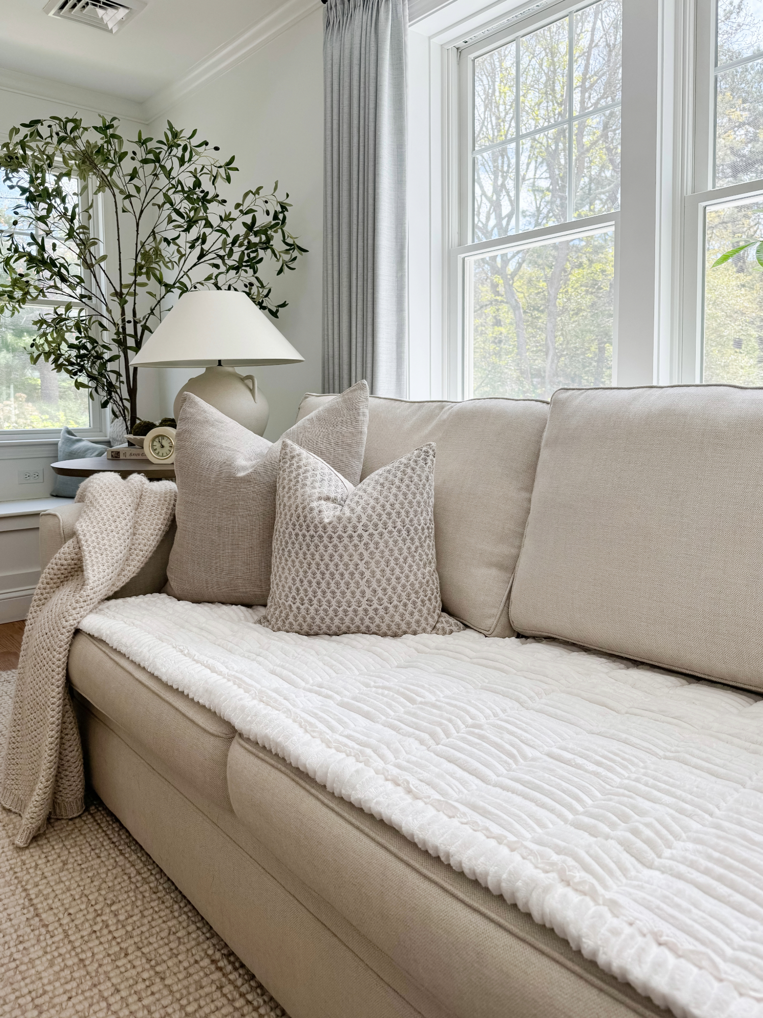 Coastal living room with beige sofa, textured throw pillows, cozy blanket, and ceramic lamp. Neutral Amazon Prime Day coastal home finds.