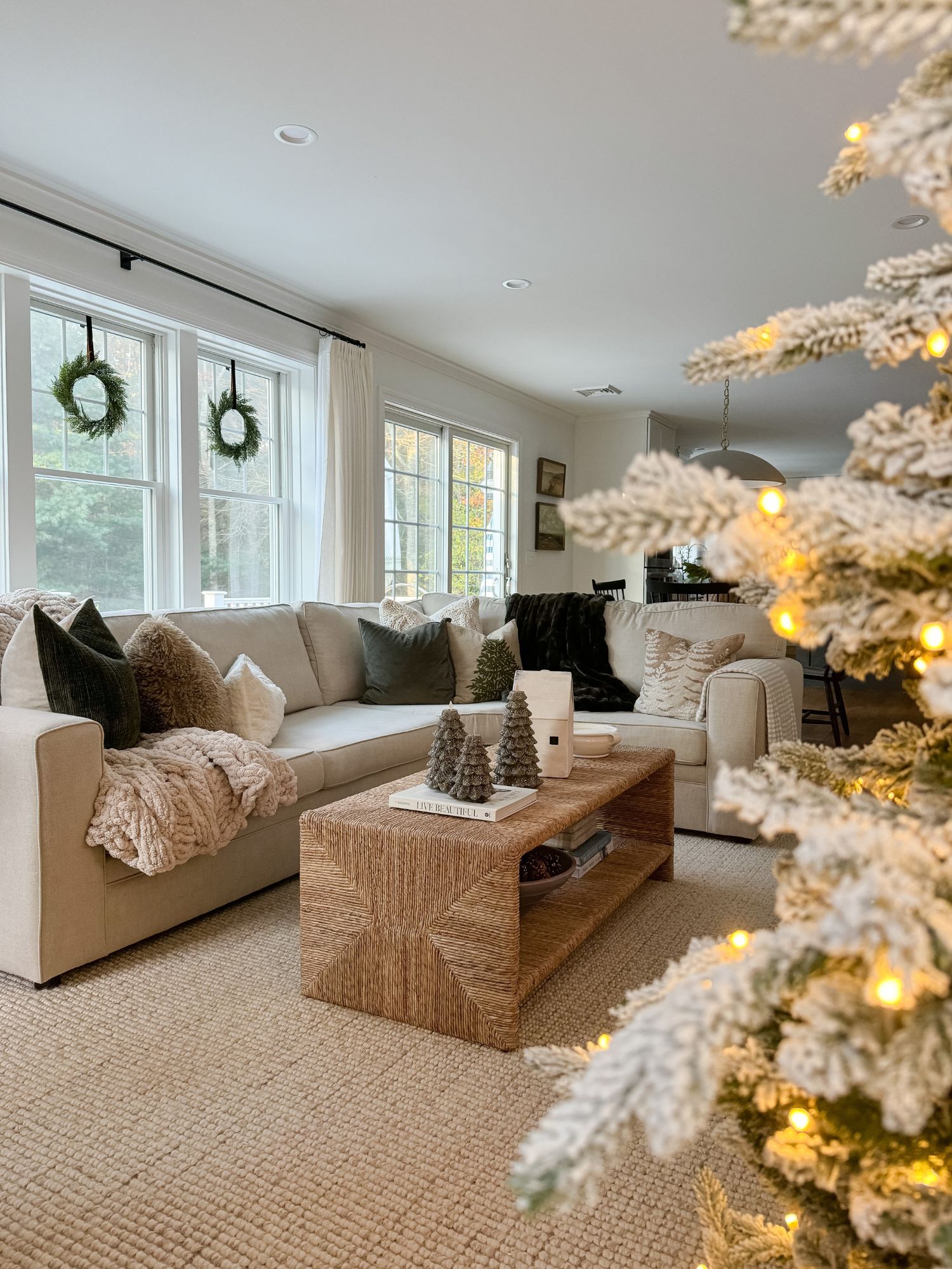 Neutral living room with a glowing Christmas tree, cozy textures, and soft lighting creating a calm, timeless holiday atmosphere.