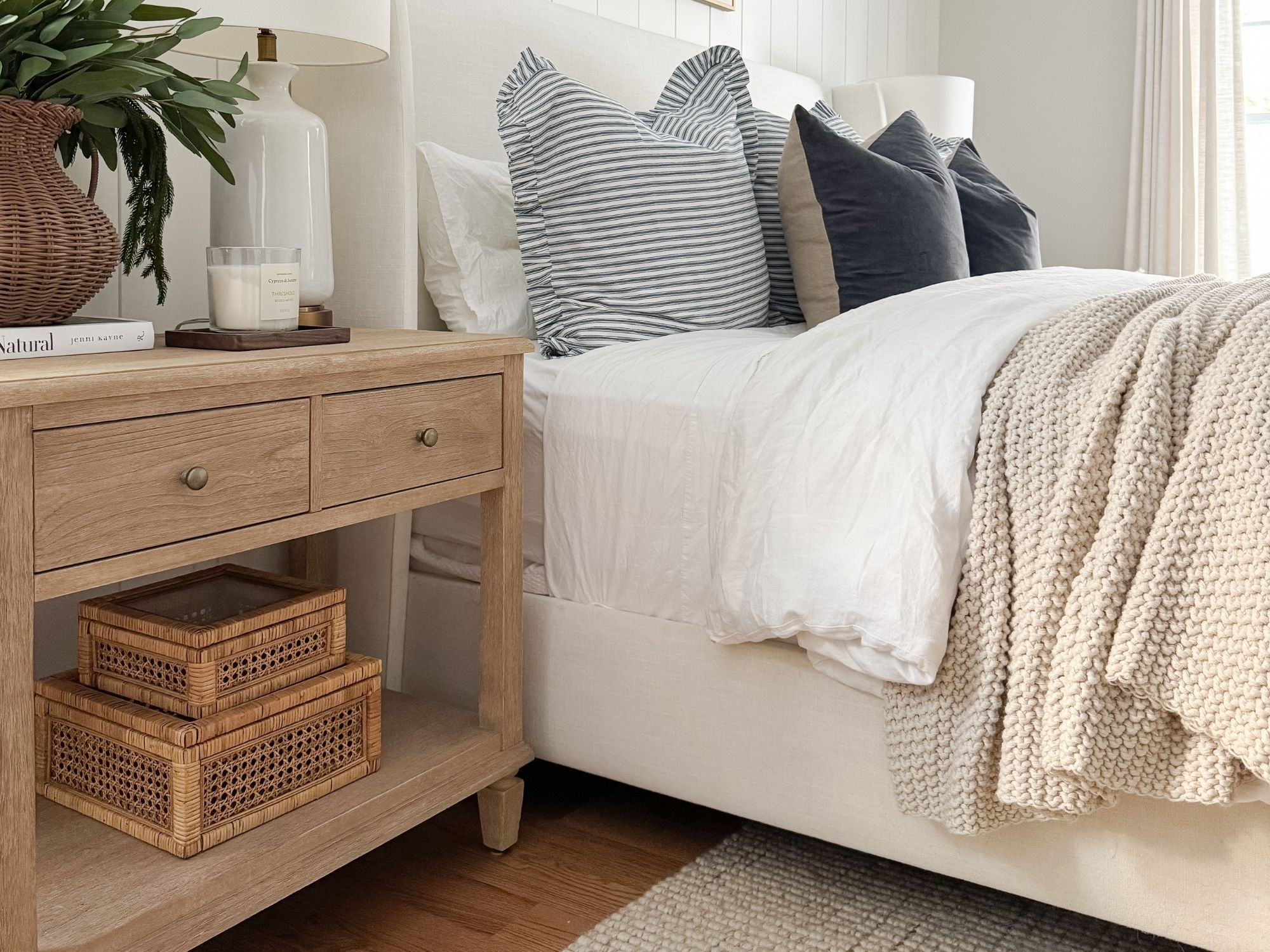 Cozy neutral bedroom with light wood nightstand, woven storage baskets, layered bedding, and soft textures designed for a family friendly home with kids and pets.