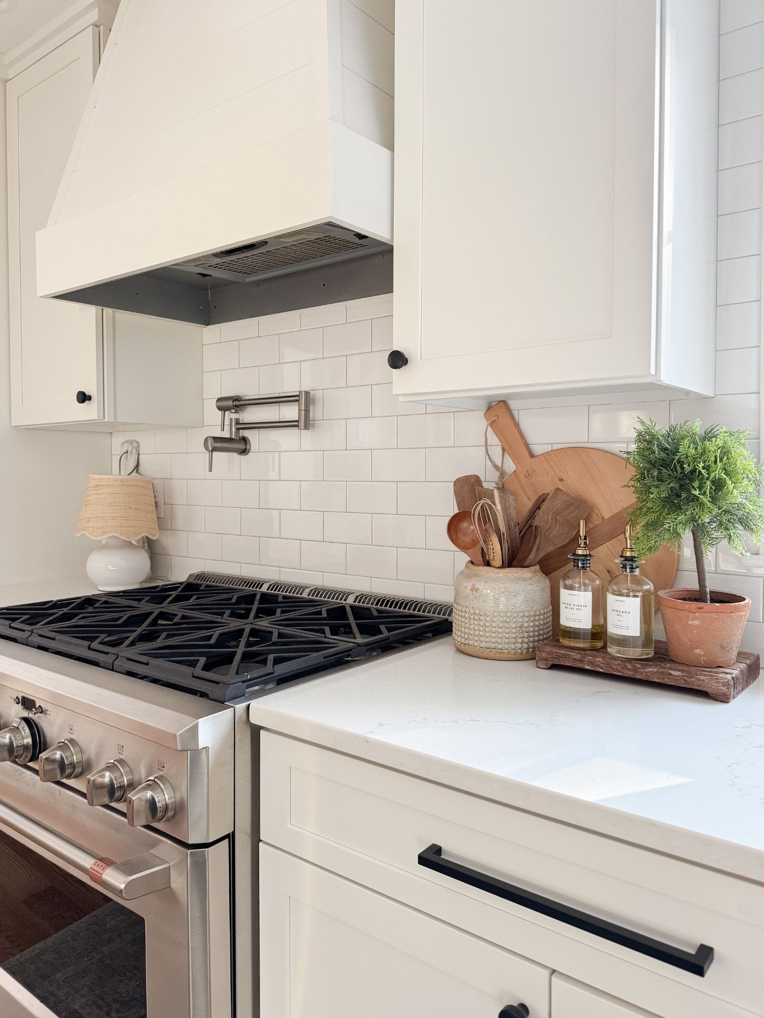 Neutral coastal kitchen vignette with wood serving boards, oil and vinegar dispensers, and layered textures in a modern Cape Cod kitchen.