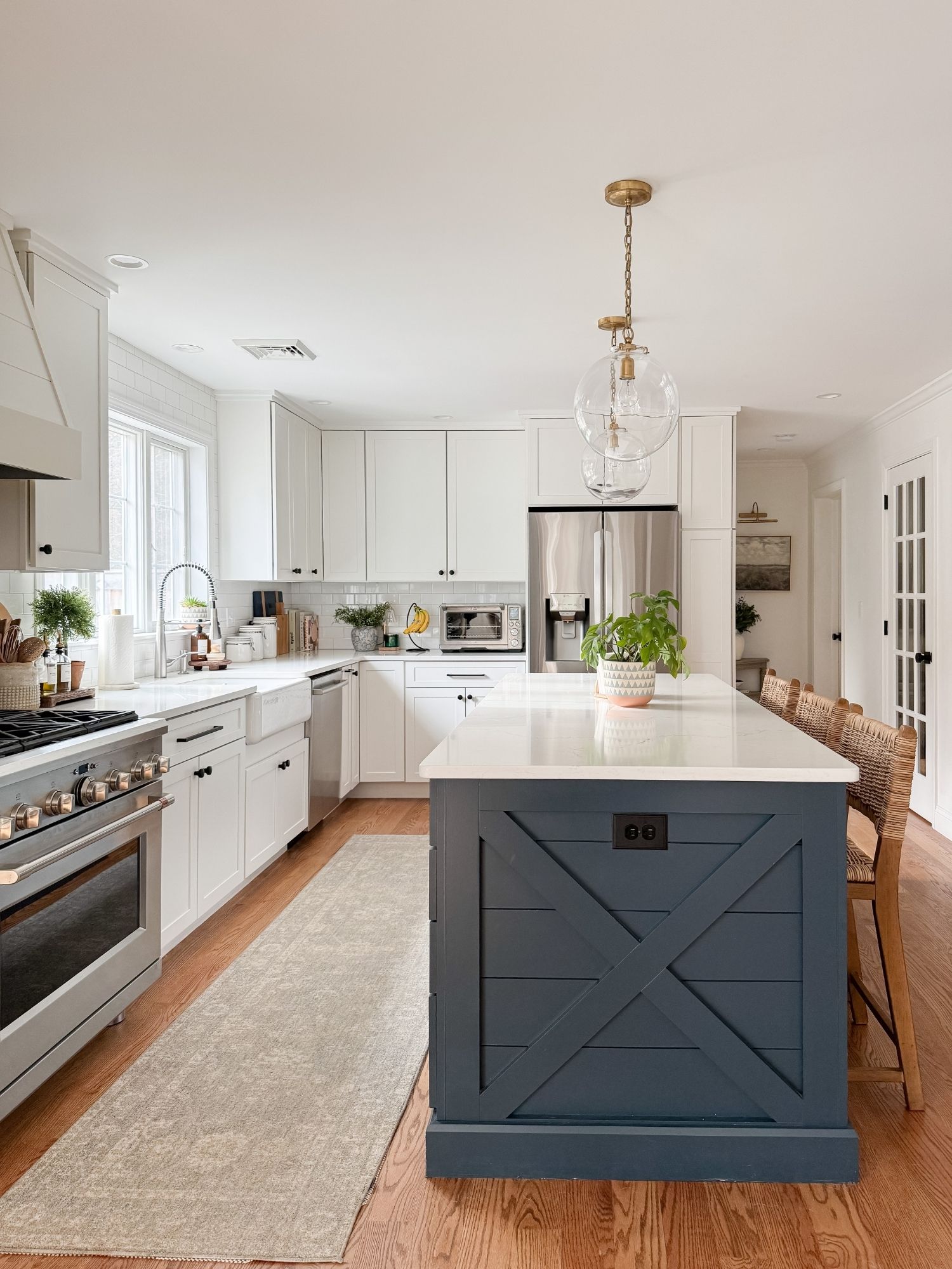 Coastal kitchen with white cabinets, navy island, neutral runner rug from Amazon, and styled kitchen decor for a high end coastal inspired home.